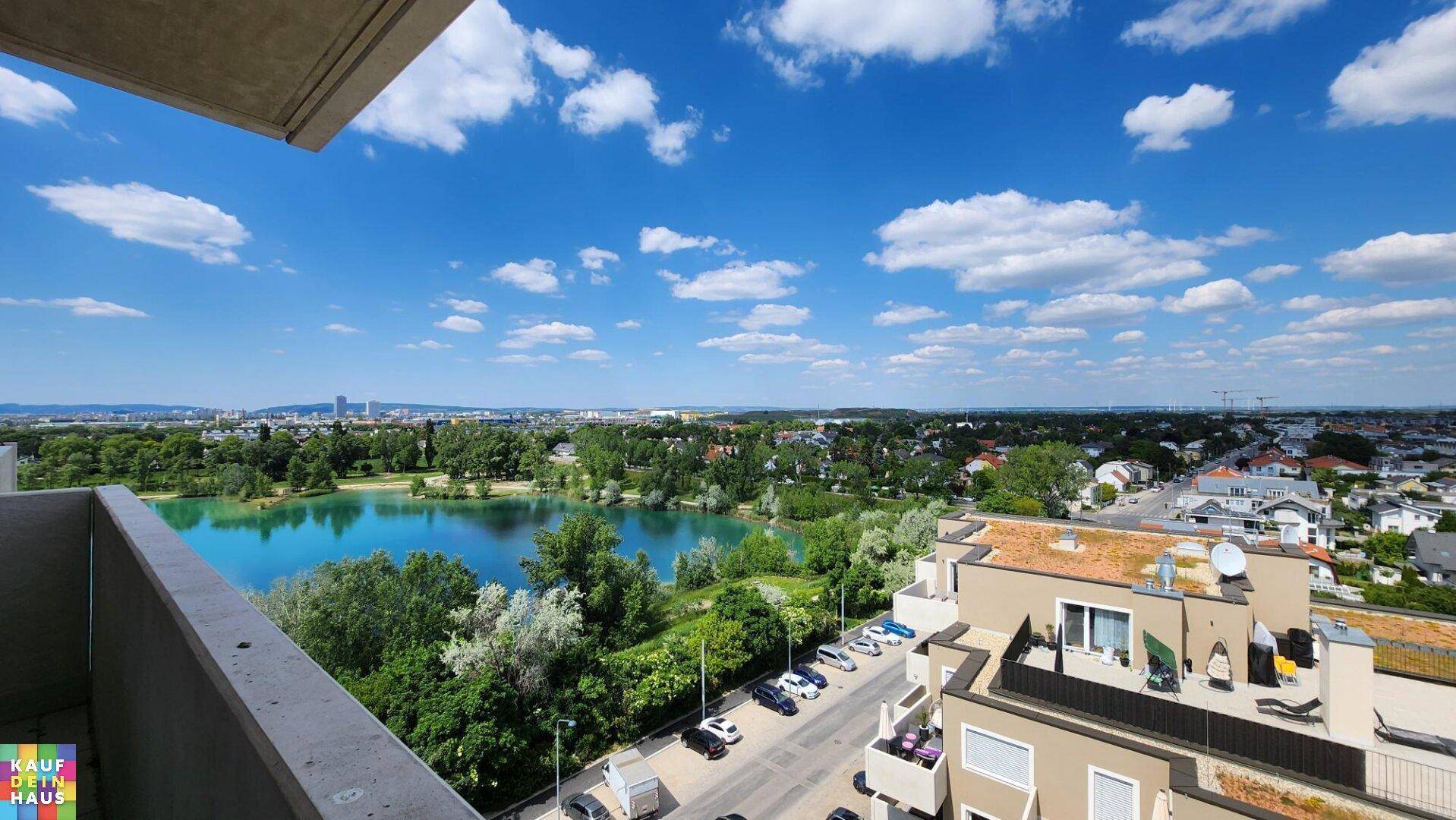 Weitläufiger Blick vom Balkon auf einen See, grüne Landschaften und die Stadt.