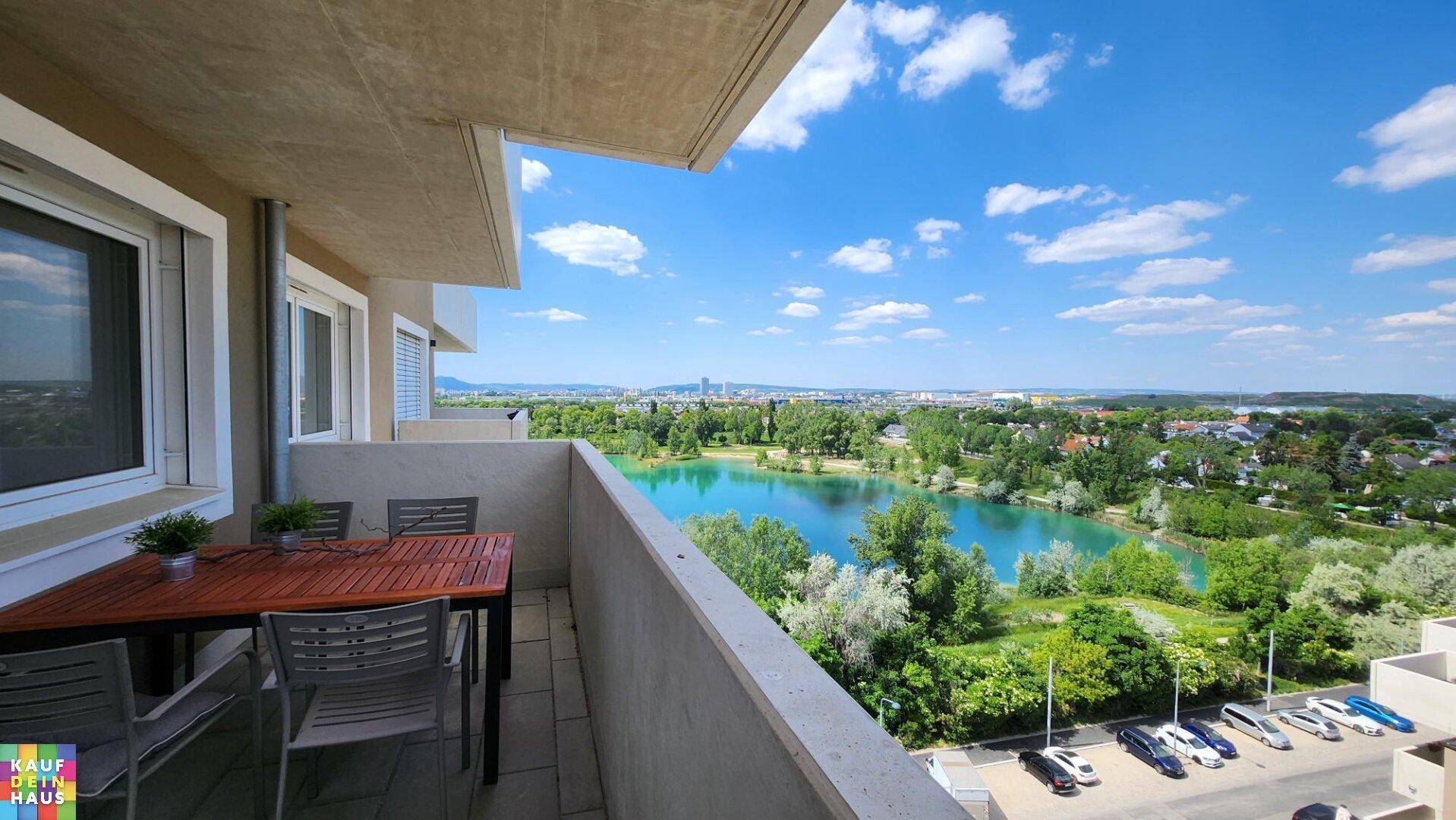 Balkon mit Esstisch und beeindruckendem Ausblick auf einen See und die Stadt.