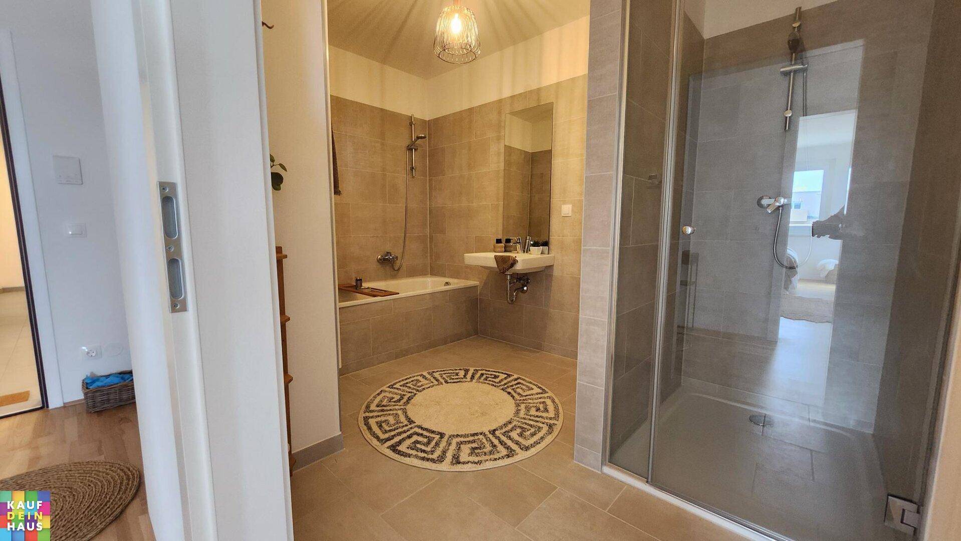 Geräumiges Badezimmer mit Badewanne, Duschkabine und modernen Fliesen.