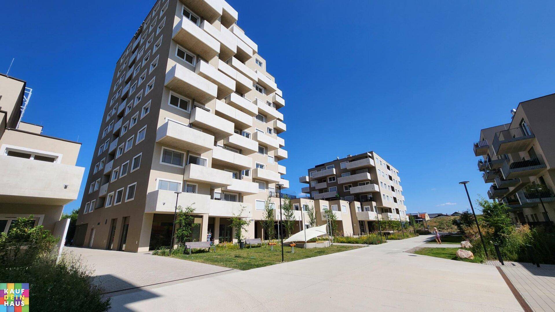 Weitläufige Ansicht eines modernen Wohnkomplexes mit mehreren Gebäuden und Wegen.