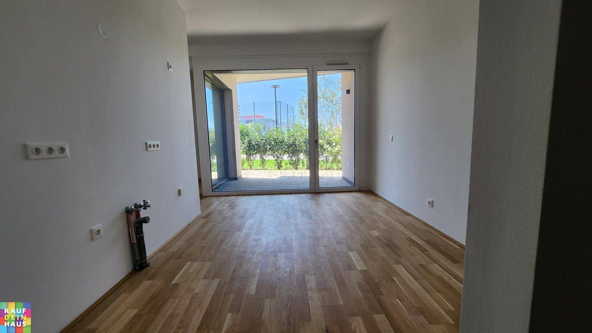 Heller Wohnraum mit Holzboden und großen Schiebetüren, die zu einer Terrasse führen.