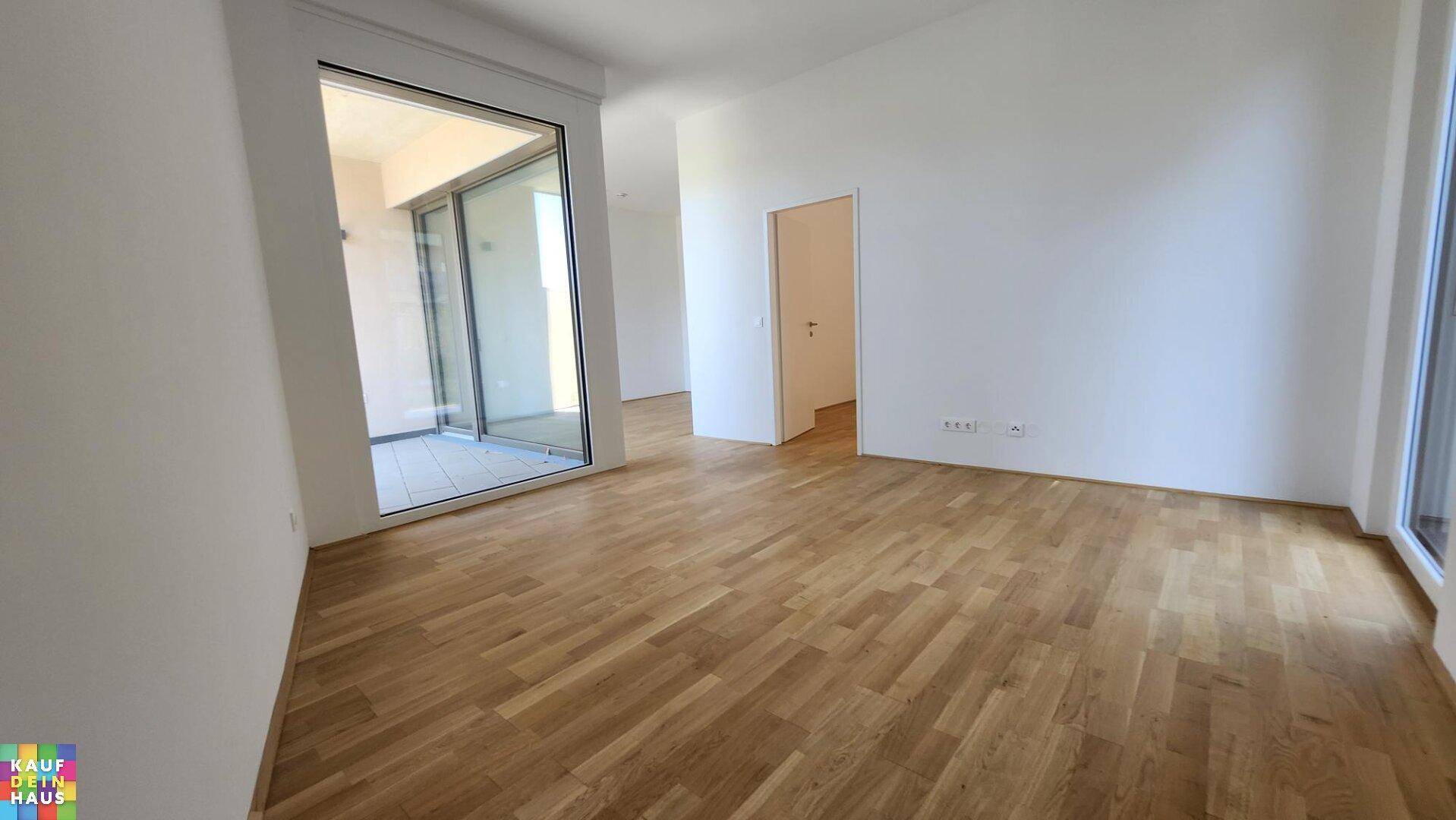 Geräumiger Wohnbereich mit Holzboden und großen Glasfronten zum Außenbereich.
