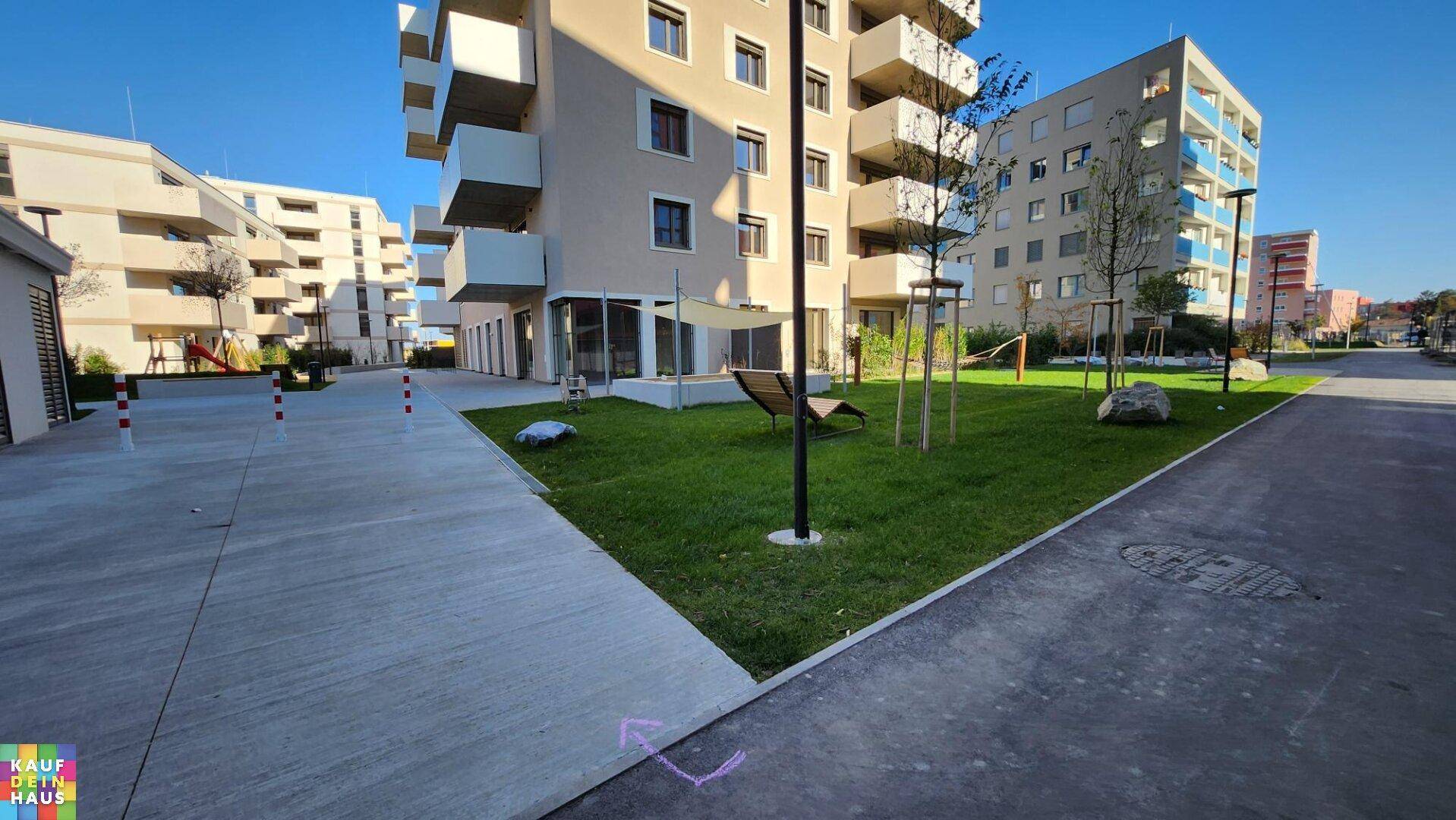 Außenansicht eines modernen Wohnkomplexes mit gepflegten Grünflächen und Gehwegen.