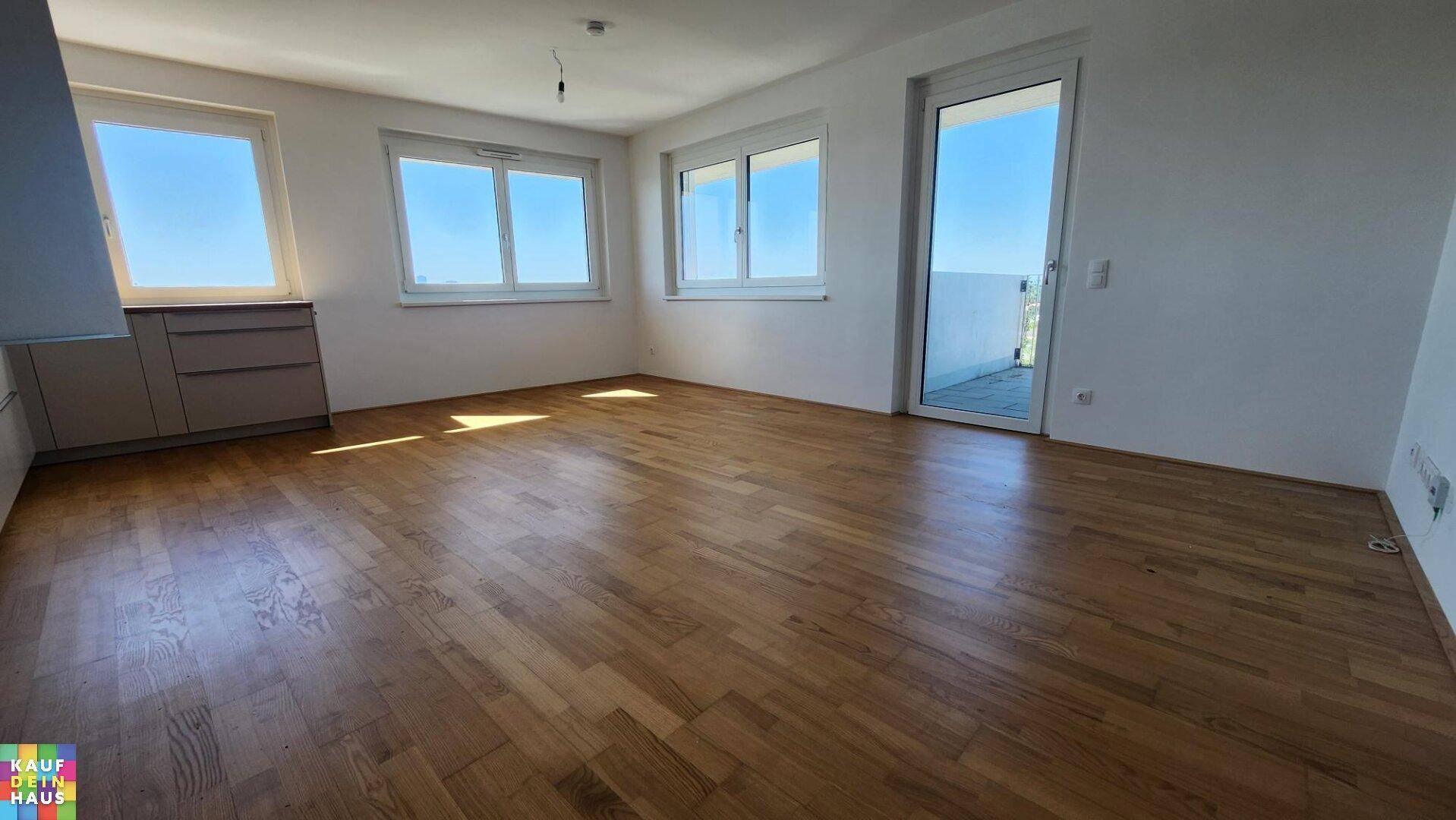 Heller Wohnraum mit Parkettboden und Zugang zu einem Balkon, der viel Tageslicht hereinlässt.