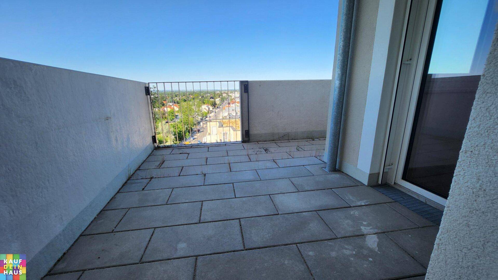 Geräumige, gepflasterte Terrasse mit Metallgeländer und Blick auf die umliegende Wohngegend.