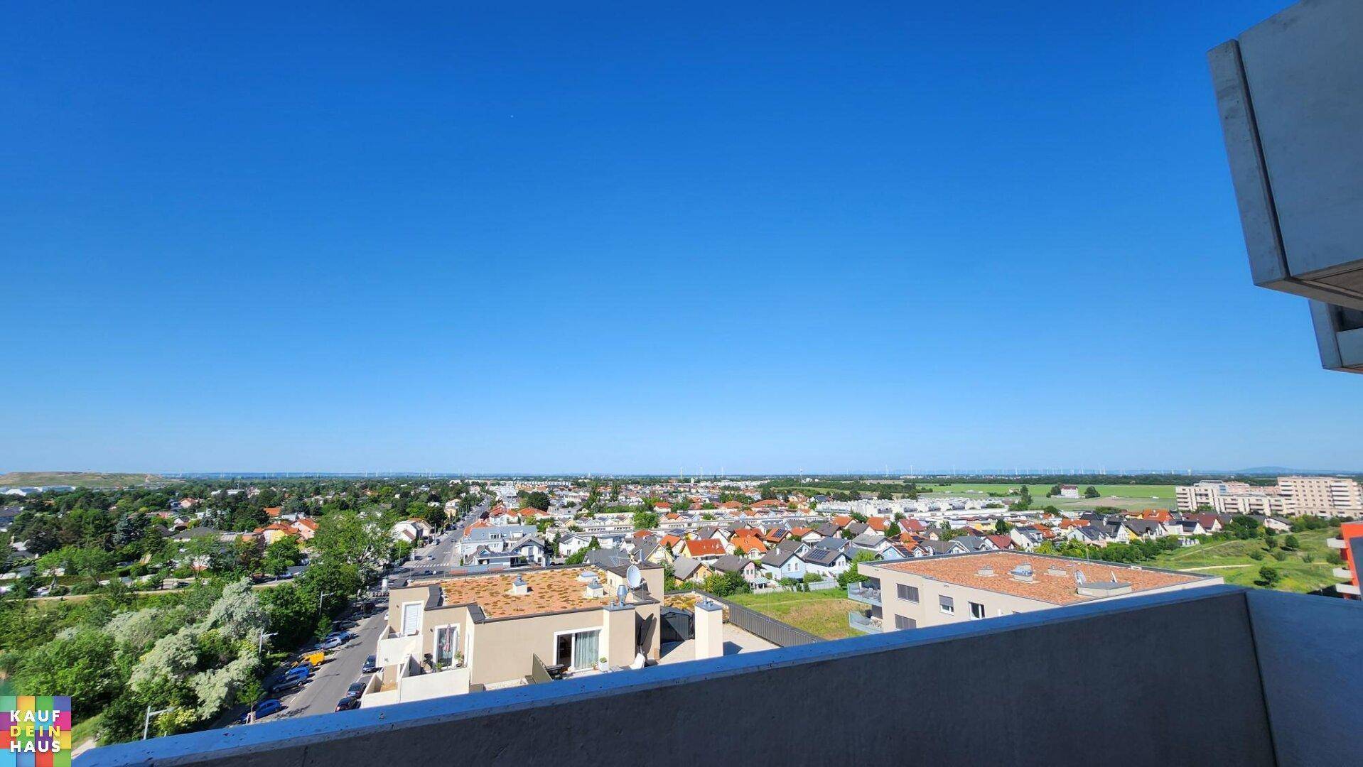 Panoramablick über eine Wohnsiedlung mit vielen Häusern und weitem Horizont an einem sonnigen Tag.