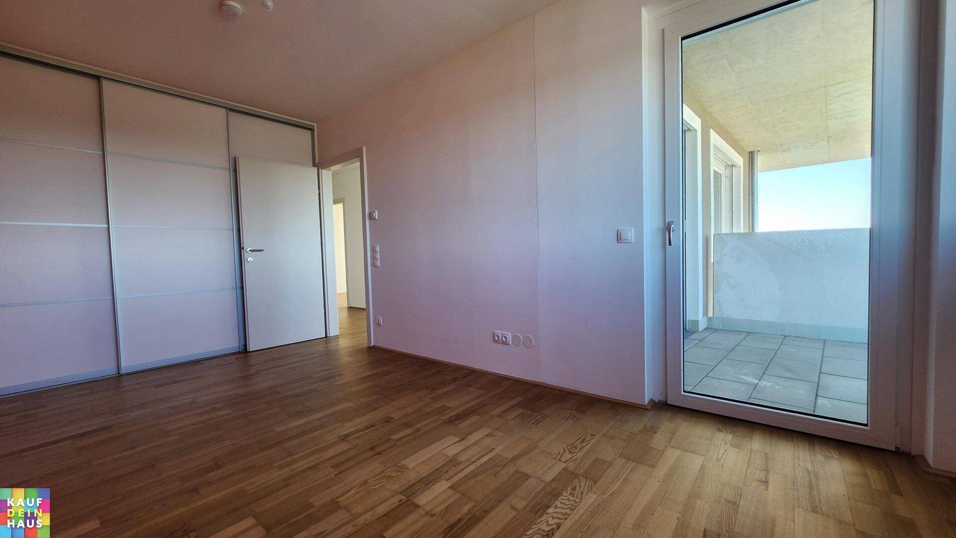 Geräumiges Zimmer mit Parkettboden, Einbauschränken und direktem Zugang zu einem Balkon.