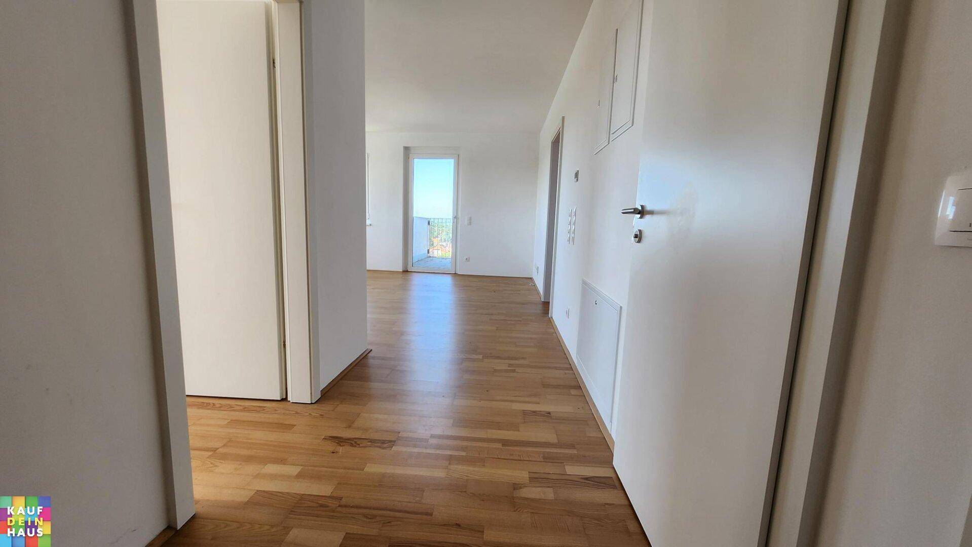 Heller Flur mit Parkettboden, der zu weiteren Räumen und einem Balkon führt.