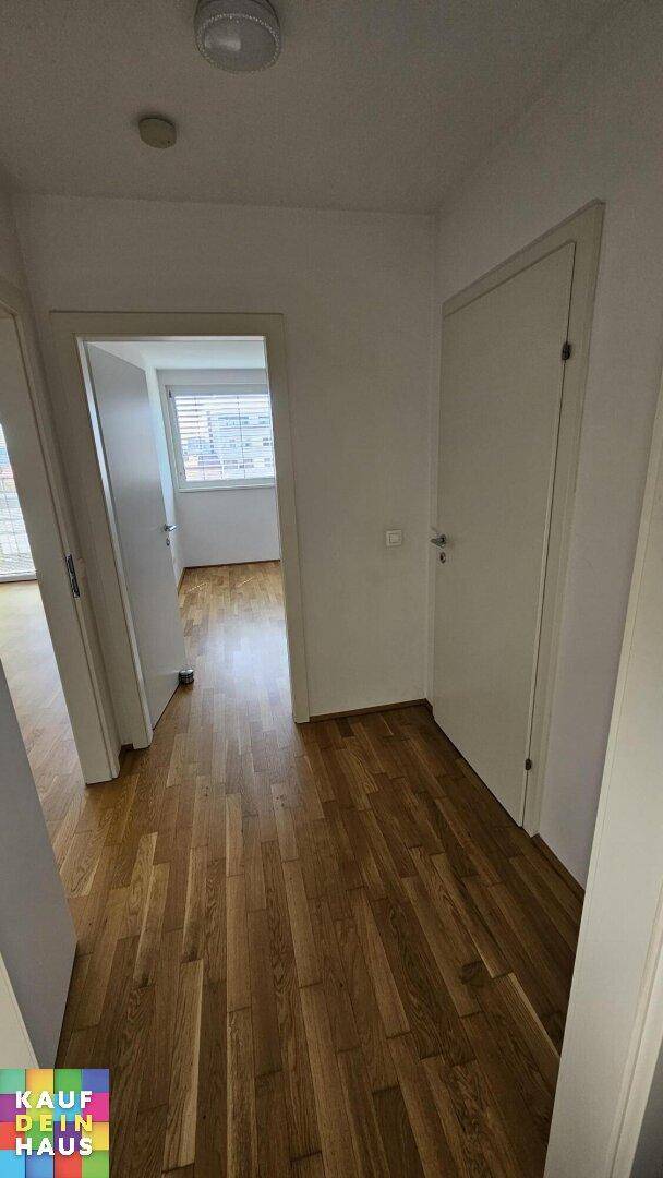 Heller Flur mit Parkettboden, der zu den verschiedenen Zimmern der Wohnung führt.