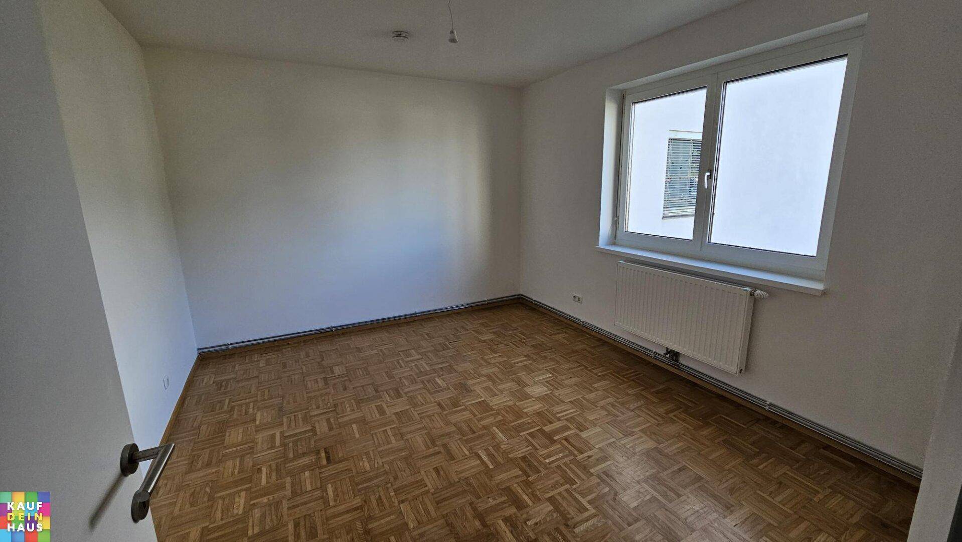 Helles Schlafzimmer mit traditionellem Parkettboden und einem großen Fenster für viel Licht.