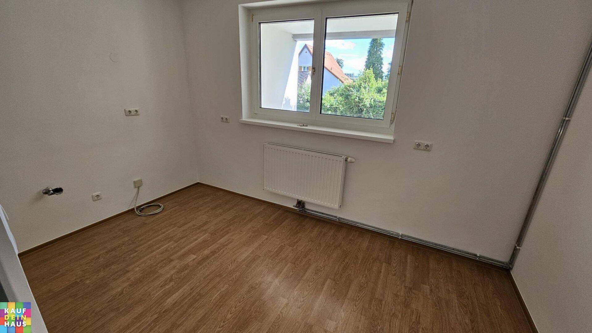 Heller Raum mit Laminatboden und Fenster, vorbereitet für die Installation einer Küche.