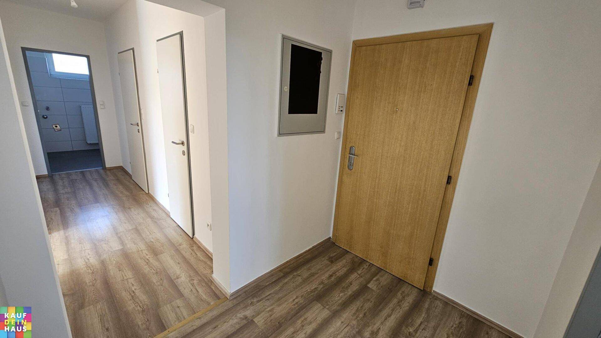Heller Flur mit Laminatboden, der zu verschiedenen Zimmern und dem Badezimmer führt.