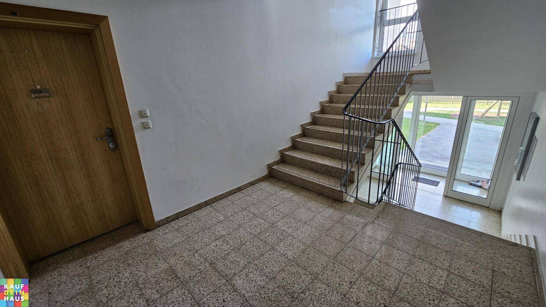 Treppenhaus mit Fliesenboden und Metallgeländer, führt zum Eingangsbereich des Gebäudes.
