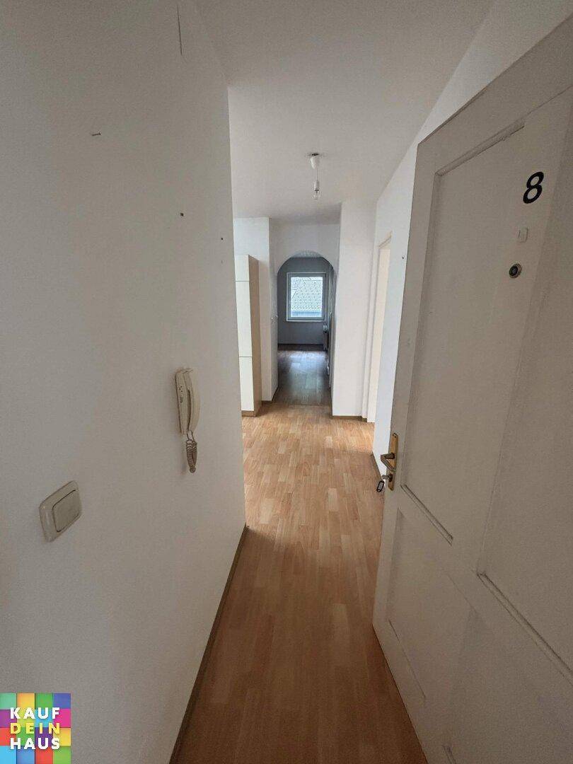 Heller Flur mit Laminatboden und Gegensprechanlage, verbindet die Wohnbereiche.
