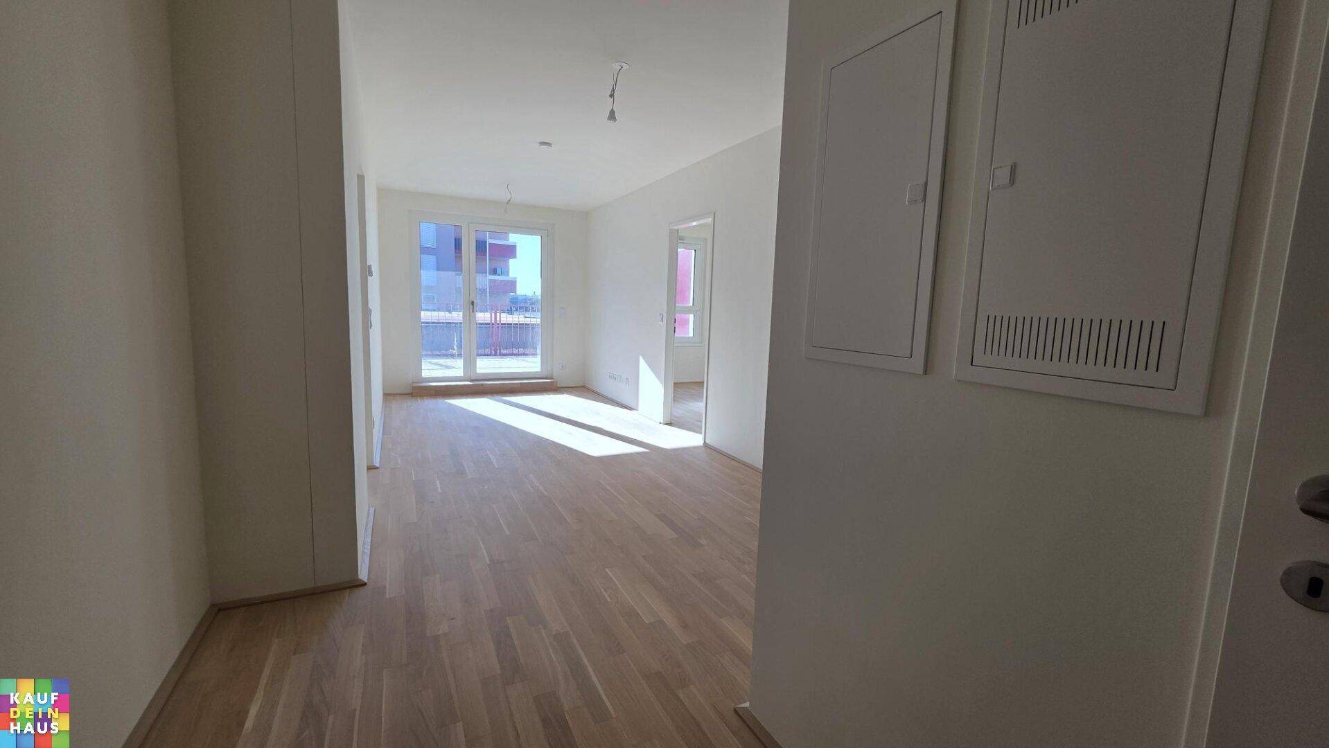 Helles, leeres Wohnzimmer mit neuem Parkettboden und Zugang zu einem Balkon oder einer Terrasse.