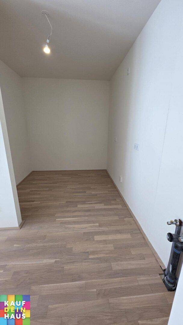 Leerer Raum mit hellem Parkettboden und weißen Wänden, bereit für die individuelle Gestaltung.