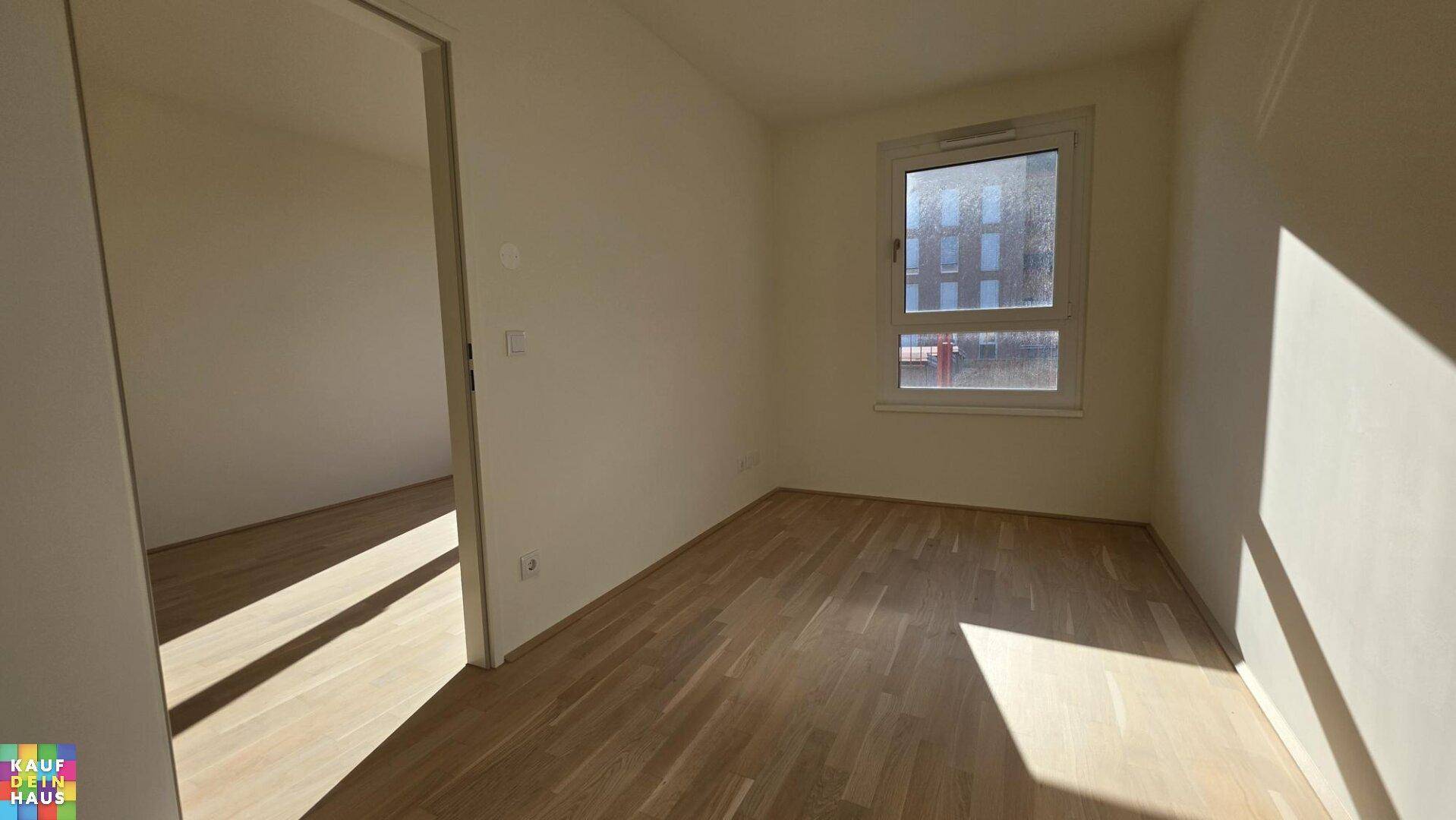 Geräumiges Schlafzimmer mit hellem Parkettboden und viel natürlichem Tageslicht.