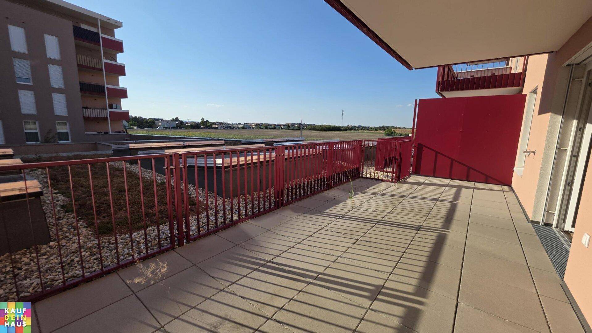 Weitläufige Terrasse mit Fliesenboden und rotem Geländer, ideal für entspannte Stunden im Freien.