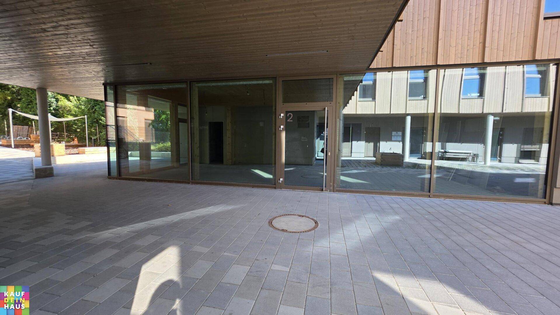 Ansicht des modernen Gebäudes mit großen Glasfenstern und Holzelementen, die einen Innenhof umgeben.