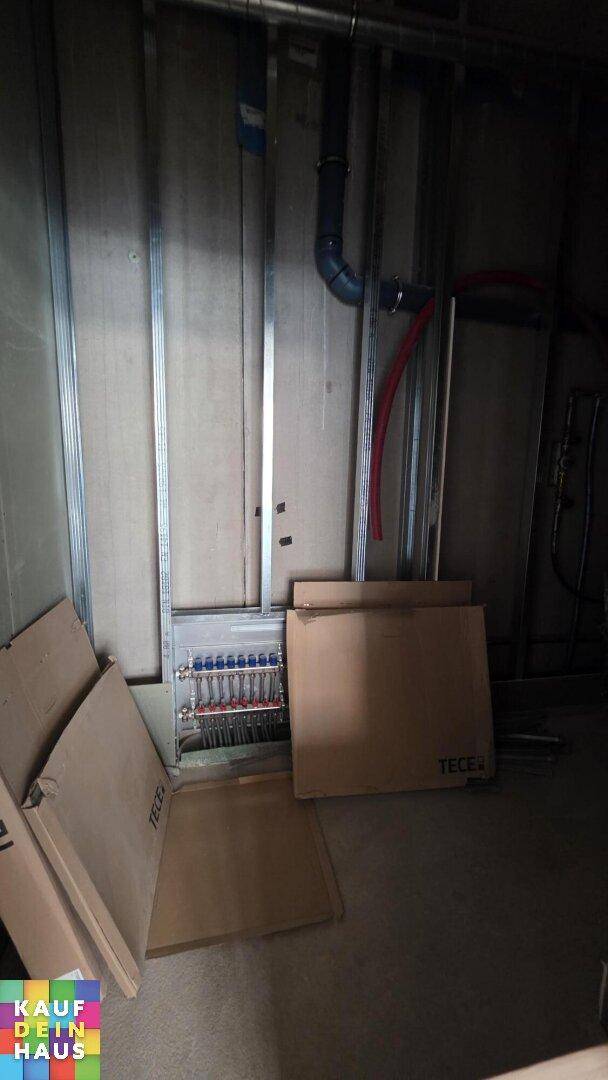 Technischer Raum im Rohbau mit sichtbaren Rohrleitungen und Installationsrahmen für zukünftige Einbauten.