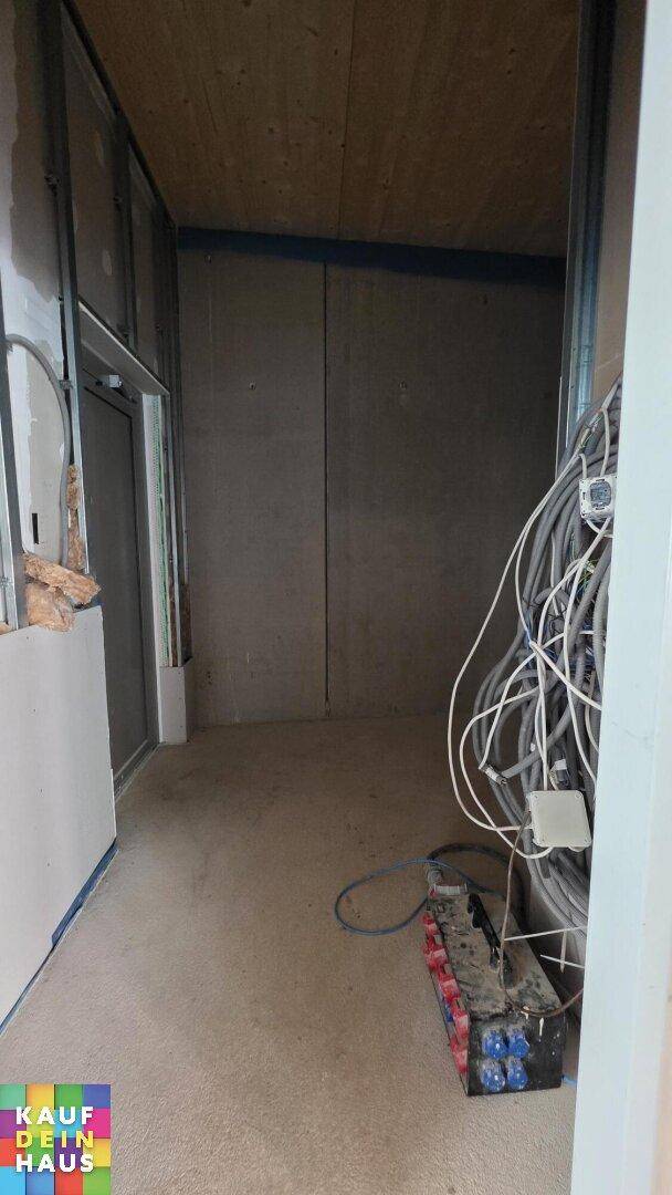 Unfertiger Technikraum mit vielen Kabeln und elektrischen Verteilern, bereit für die Fertigstellung.