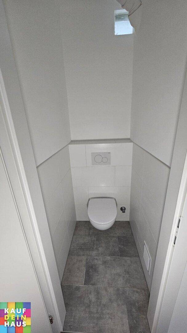 Separates WC mit Wand-WC und Fliesenboden, ideal für Gäste.