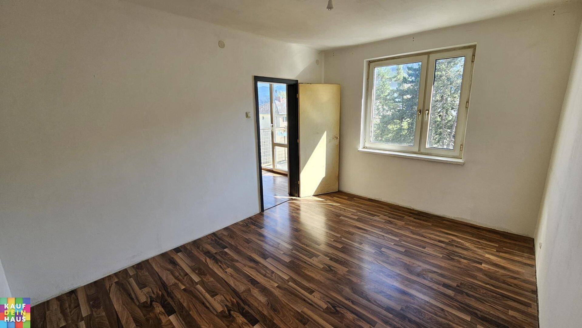 Geräumiges Zimmer mit Laminatboden und großem Fenster, geeignet als Schlaf- oder Gästezimmer.