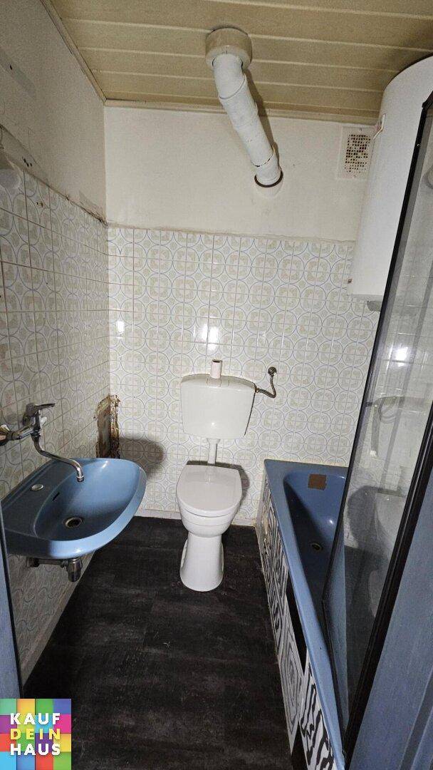 Kleines Badezimmer mit blauen Sanitärobjekten und gemusterten Fliesen, benötigt Modernisierung.