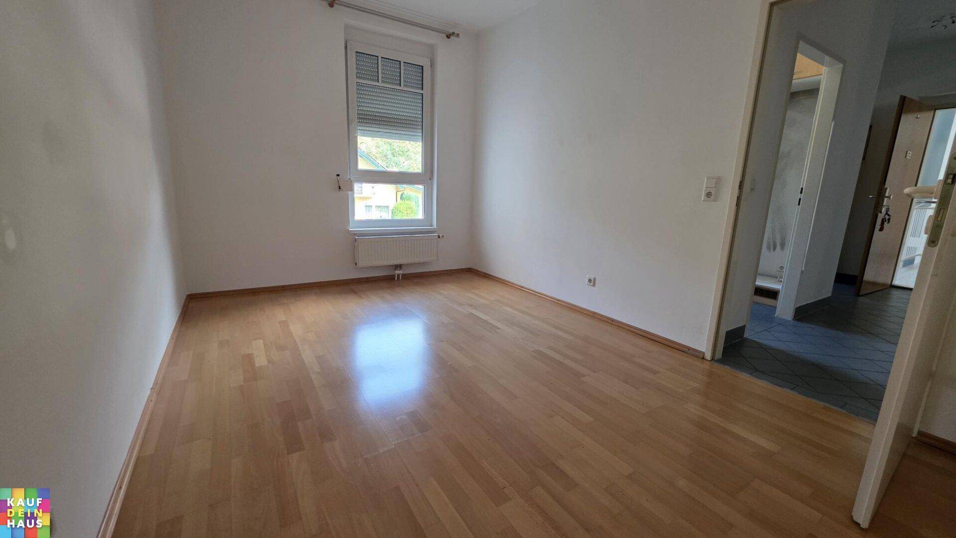 Helles Zimmer mit Laminatboden und Fenster mit Rollladen, bereit zur individuellen Gestaltung.