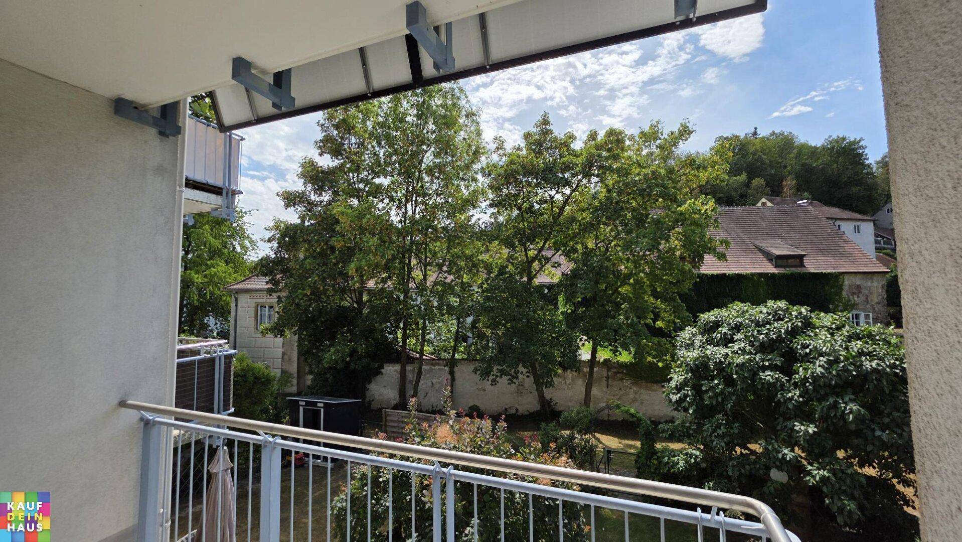 Balkon mit Blick auf grüne Bäume und umliegende Häuser, ideal zum Entspannen im Freien.