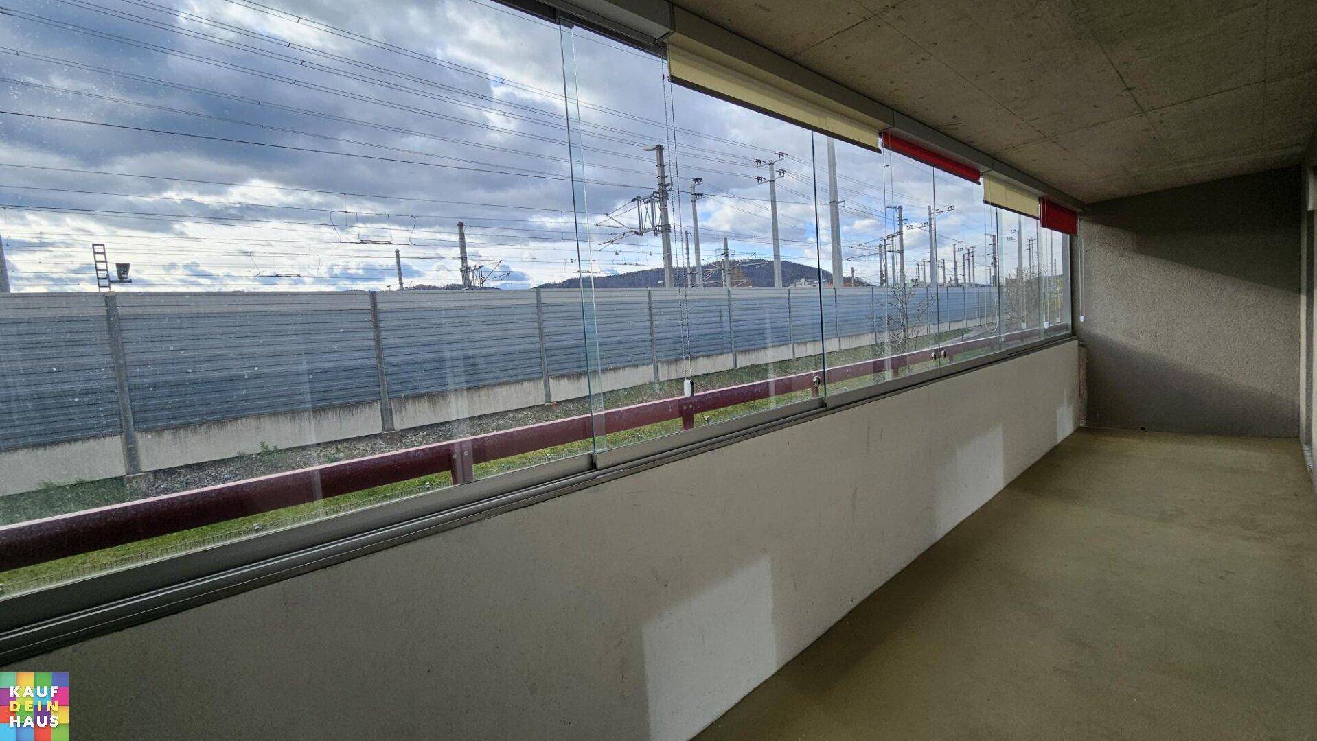 Verglaste Loggia mit Blick auf die Umgebung und ferne Berge, ideal für entspannte Stunden im Freien.