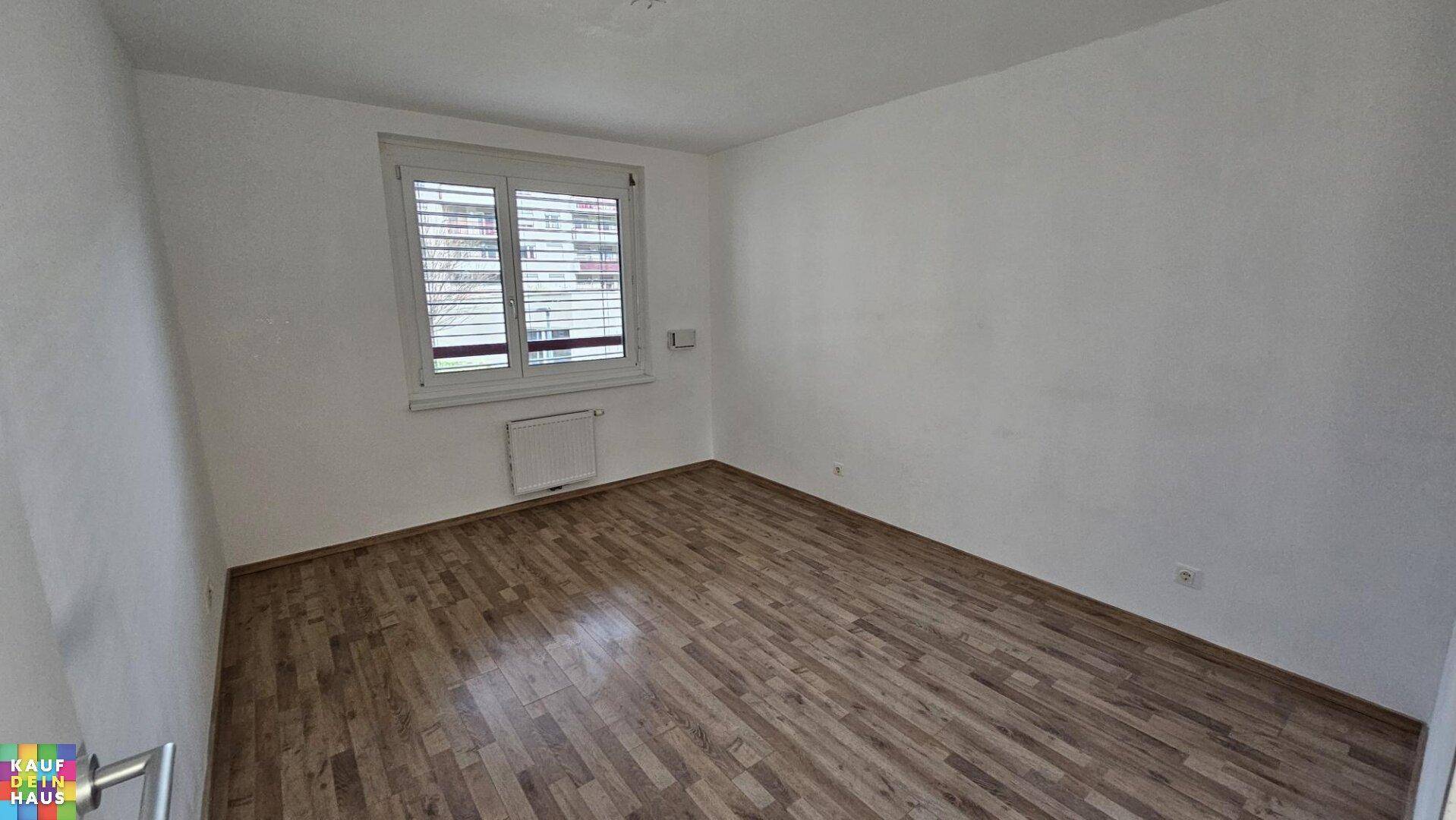 Ruhiges Schlafzimmer mit Holzboden und einem Fenster mit Jalousien für Privatsphäre und Lichtregulierung.