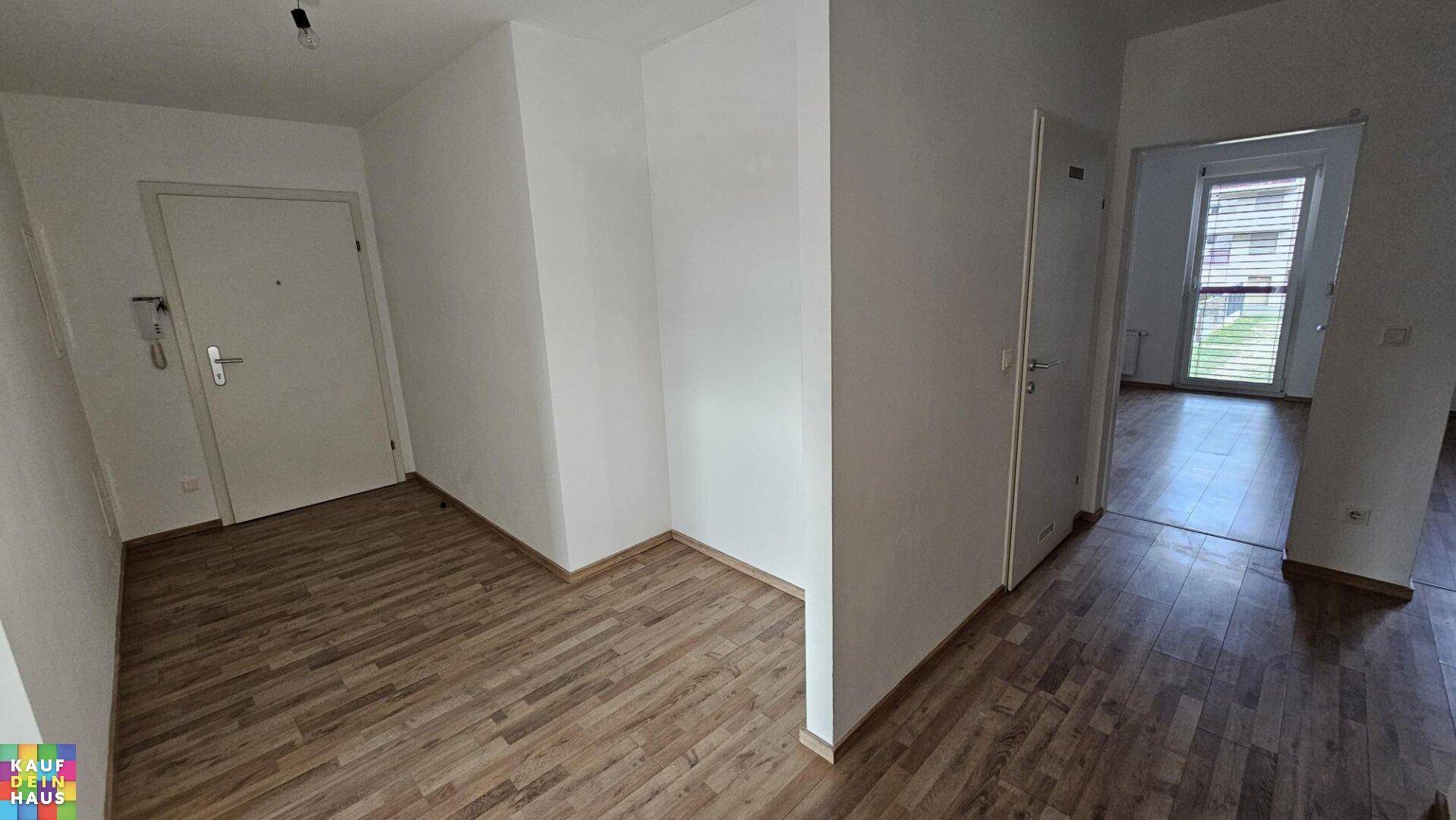 Heller Flur mit Holzboden und Gegensprechanlage, der die verschiedenen Räume der Wohnung verbindet.
