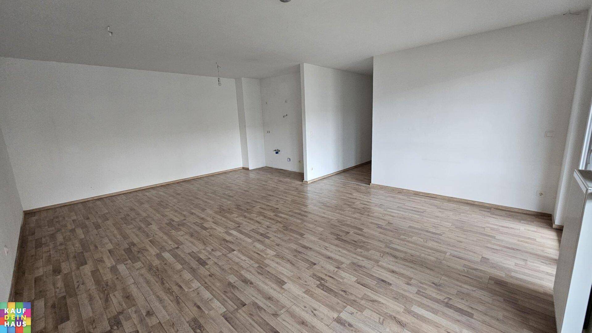 Geräumiges Wohnzimmer mit Holzboden und weißen Wänden, bereit zur individuellen Gestaltung.