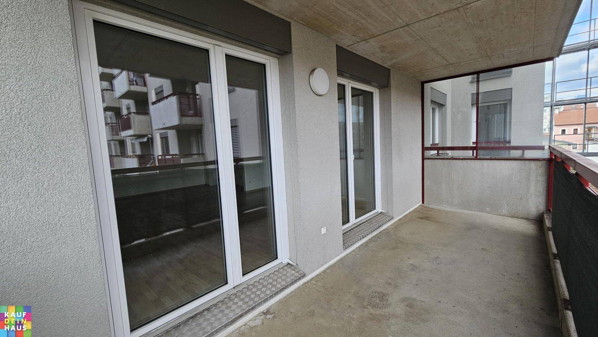 Balkon mit Schiebetüren und Blick auf die umliegende Wohnbebauung.