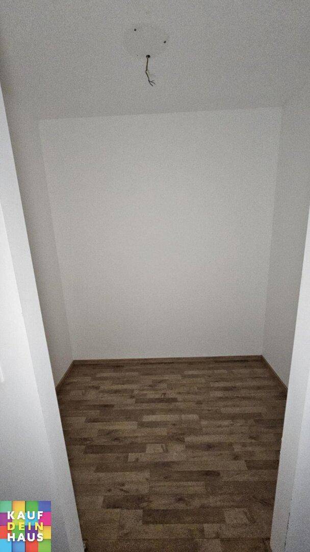 Kleiner, leerer Abstellraum mit Holzboden und weißen Wänden.