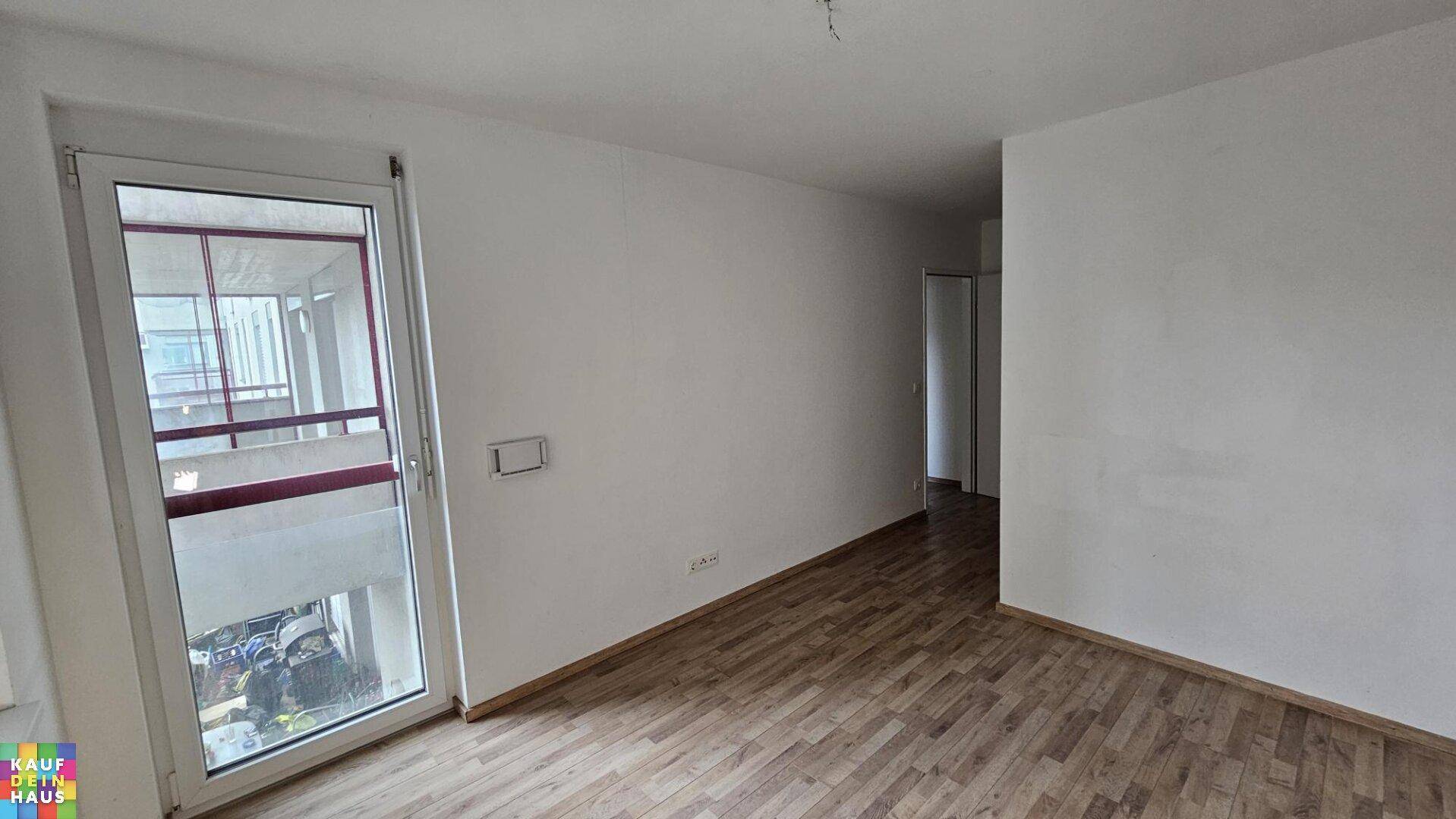 Leeres Zimmer mit Holzboden und Zugang zu einem Außenbereich, ideal als Schlafzimmer.