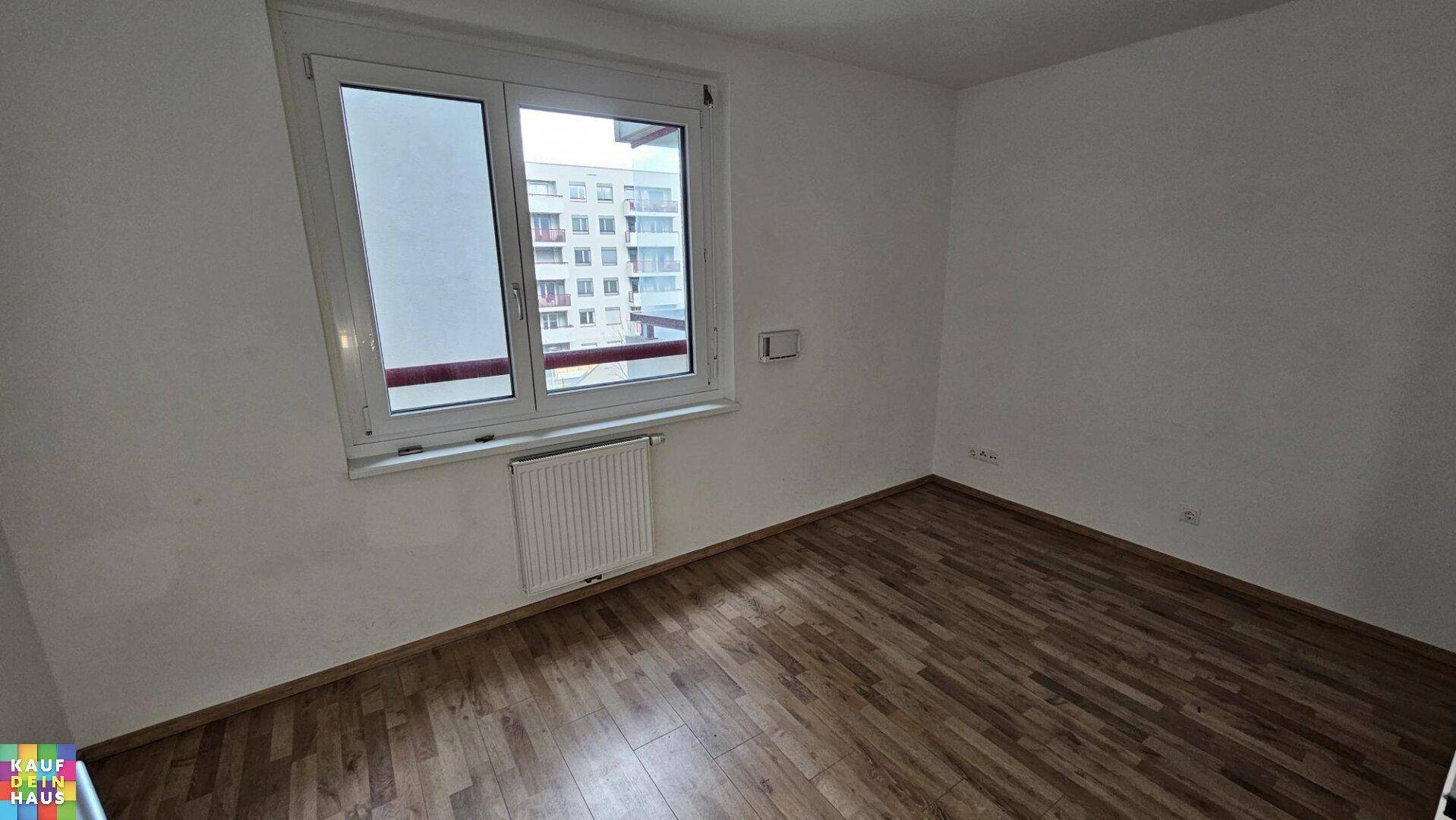 Weiteres helles Schlafzimmer mit Holzboden, Fenster und Heizkörper.