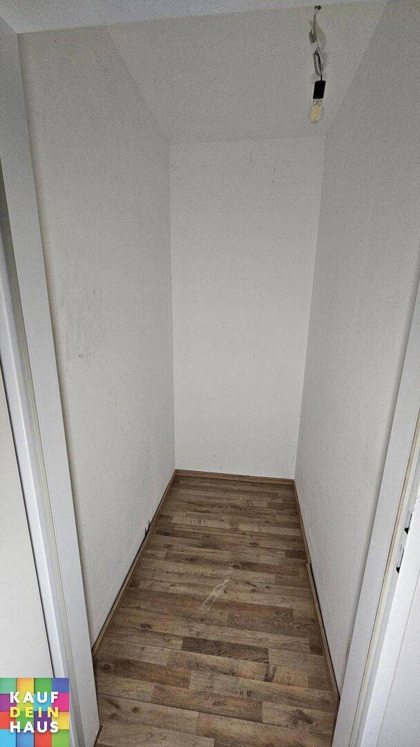 Schmaler Abstellraum mit Holzboden und weißen Wänden, ideal für zusätzlichen Stauraum.