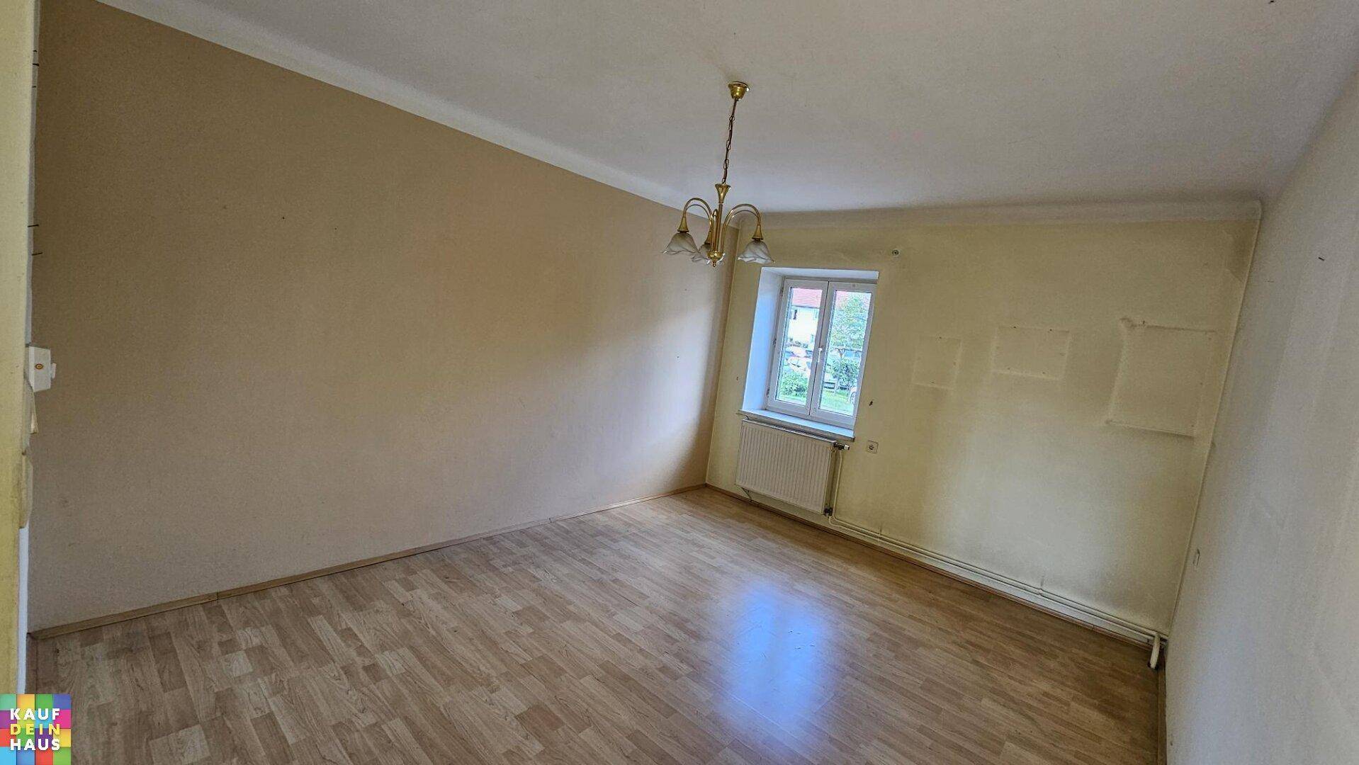 Geräumiges Zimmer mit Laminatboden und einem Fenster, das viel Tageslicht hereinlässt.