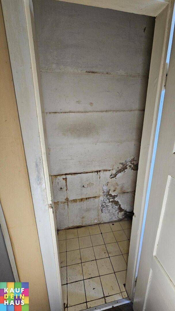 Einfacher Abstellraum im Keller mit Fliesenboden und unverputzten Wänden, ideal für Lagerzwecke.