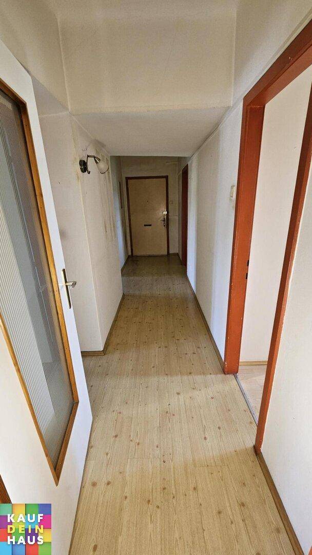 Langer, heller Flur mit Laminatboden und mehreren Türen, die zu den Wohnräumen führen.