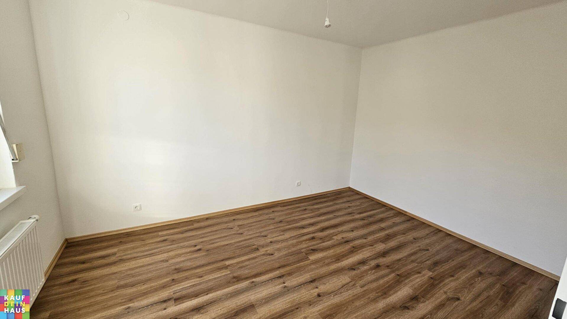 Geräumiges Schlafzimmer mit Laminatboden und einem Fenster für natürliches Licht.