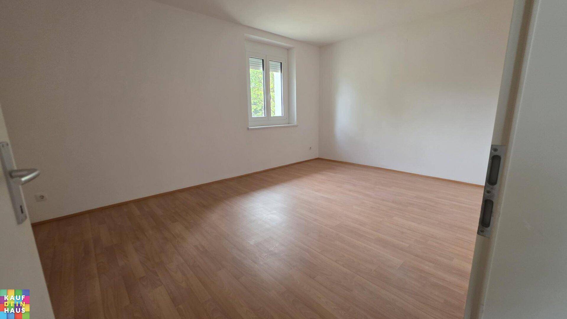 Geräumiges Zimmer mit Laminatboden und einem Fenster mit Rollladen, ideal als Schlaf- oder Arbeitszimmer.