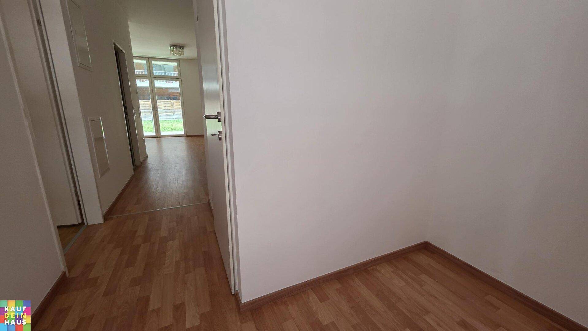 Heller Flur mit Laminatboden, weißen Wänden und Zugang zu weiteren Räumen.