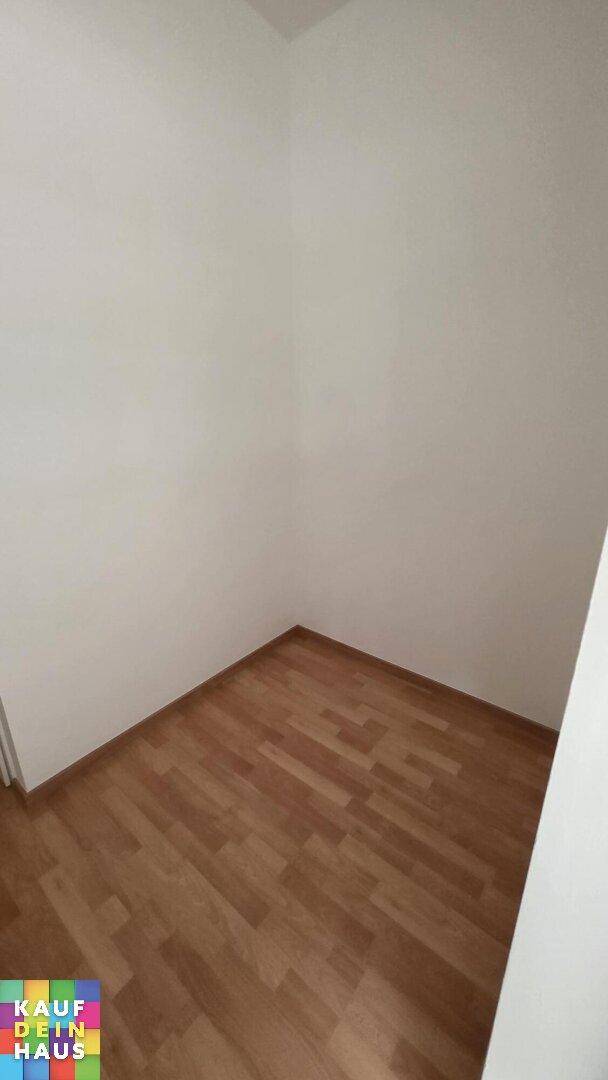 Leerer Raum mit hellem Laminatboden und weißen Wänden, bereit zur individuellen Gestaltung.