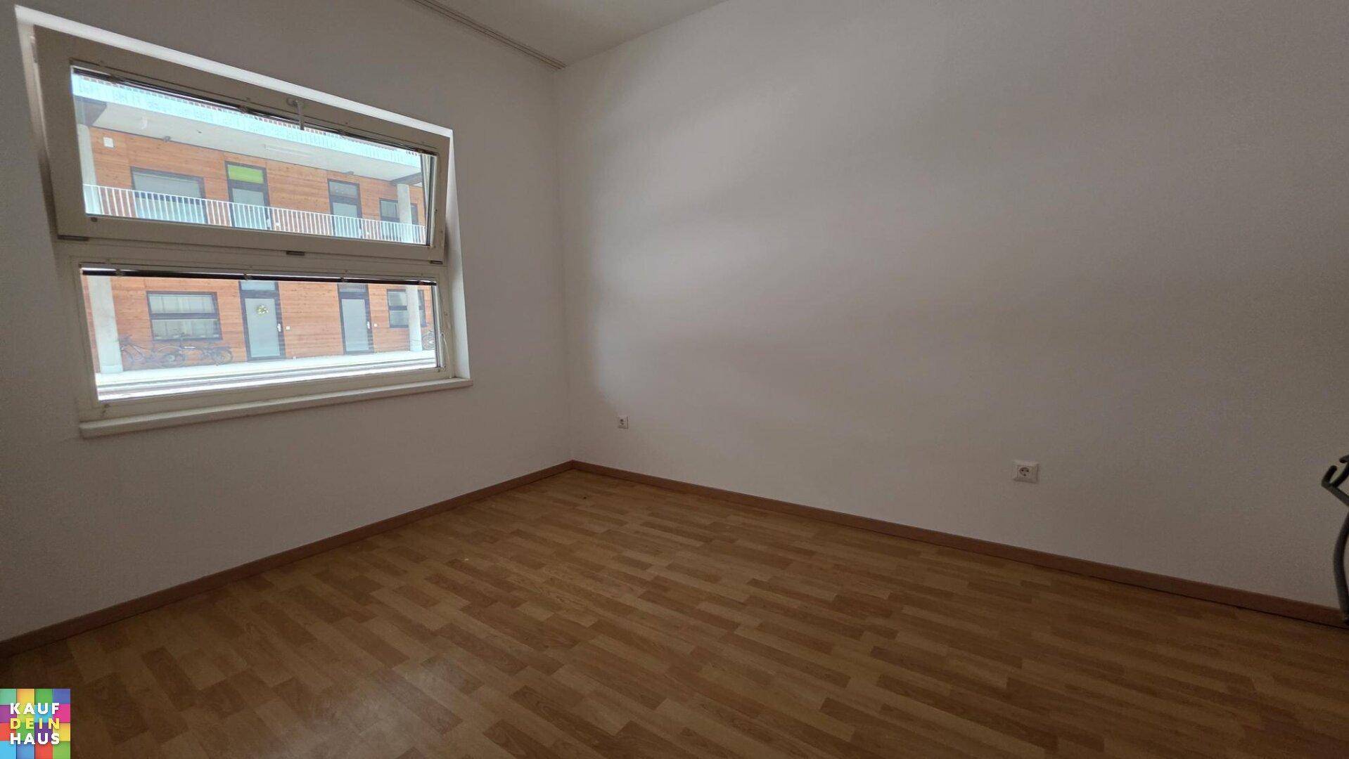 Helles Schlafzimmer mit Laminatboden und Fenster, das einen Blick auf die Umgebung bietet.