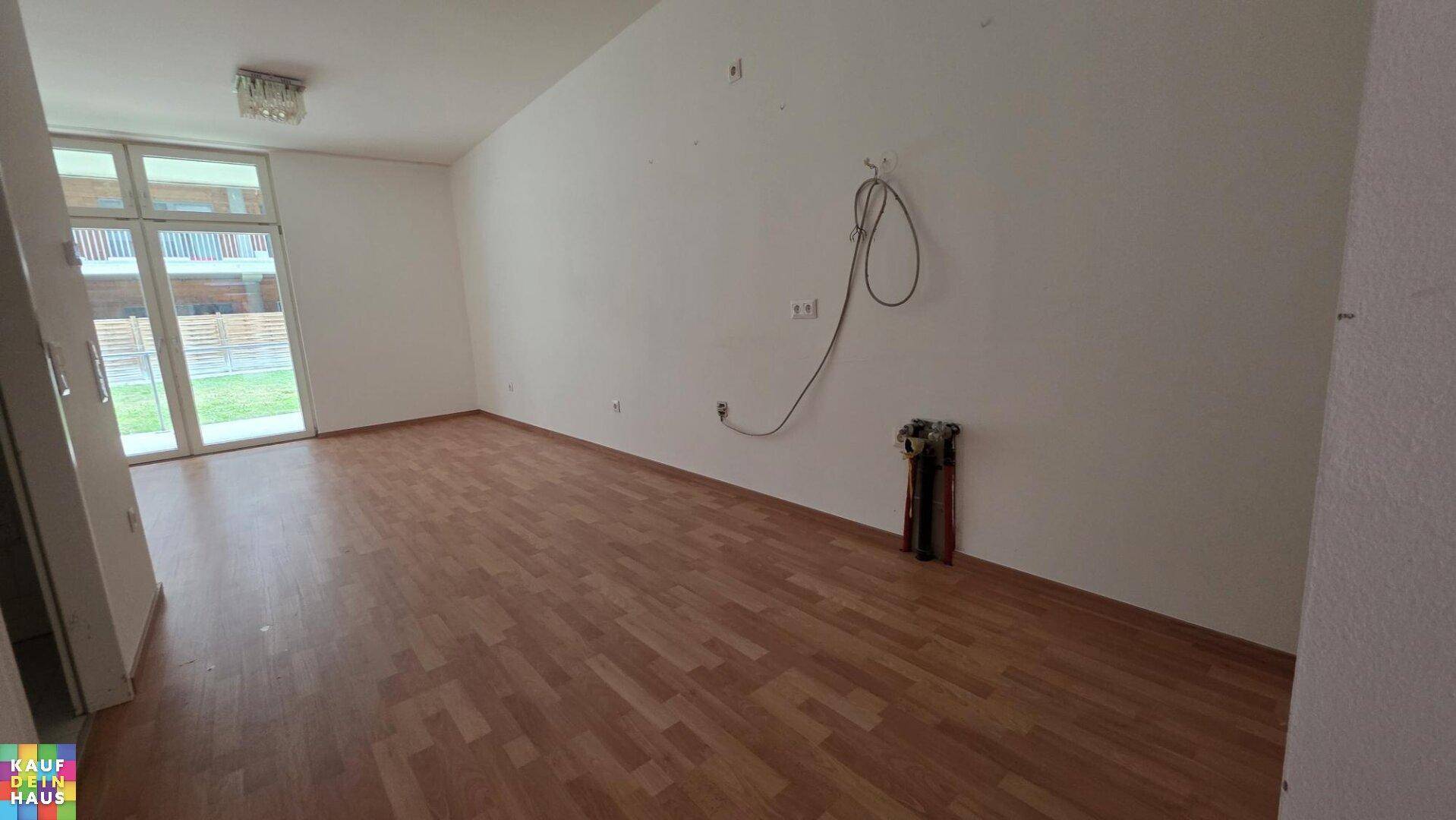 Geräumiger Wohnbereich mit Laminatboden und Zugang zu einem Außenbereich, bereit für Installationen.