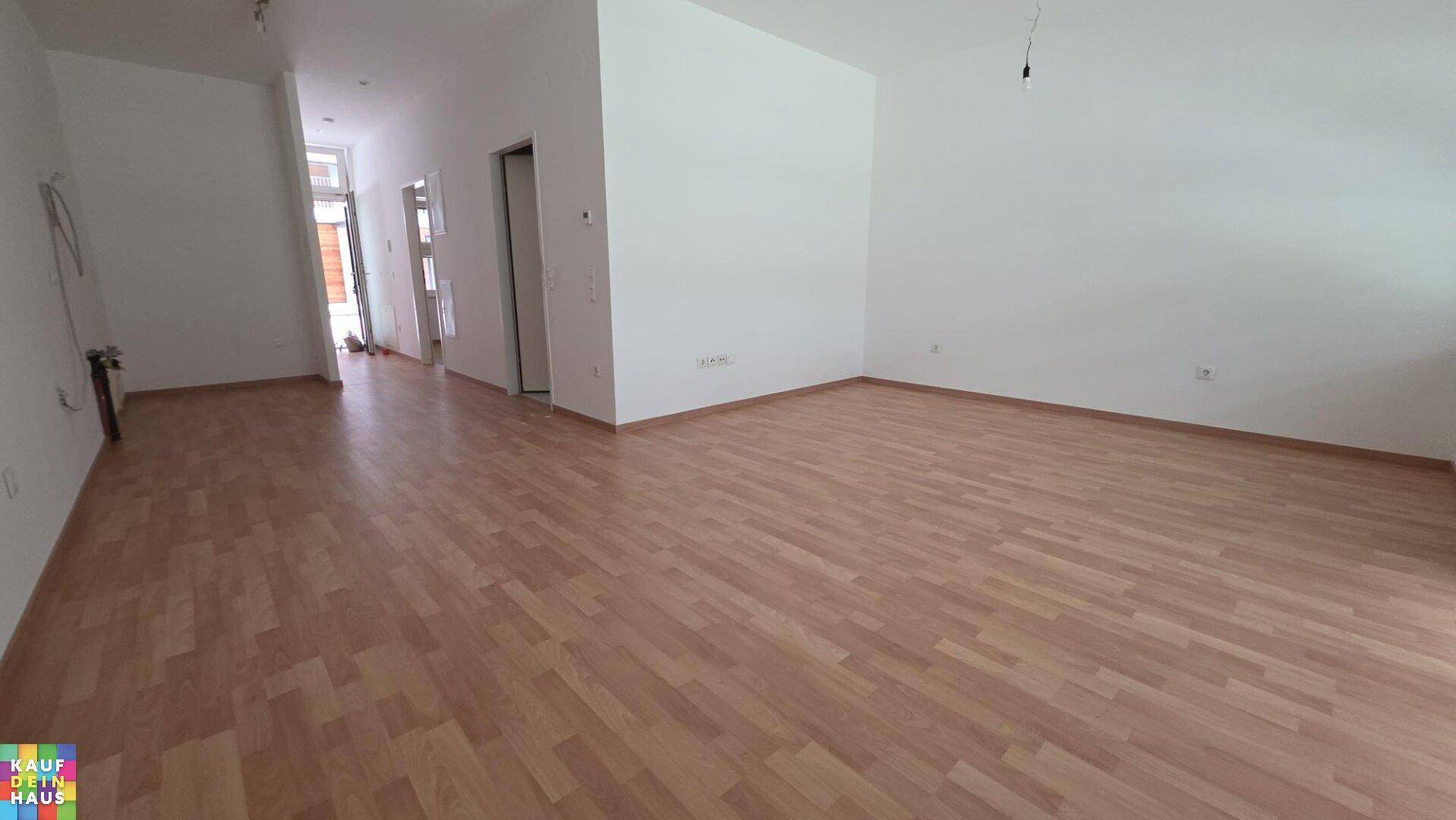 Großzügiger Wohnbereich mit Laminatboden und hellem Ambiente, ideal für offenes Wohnen.