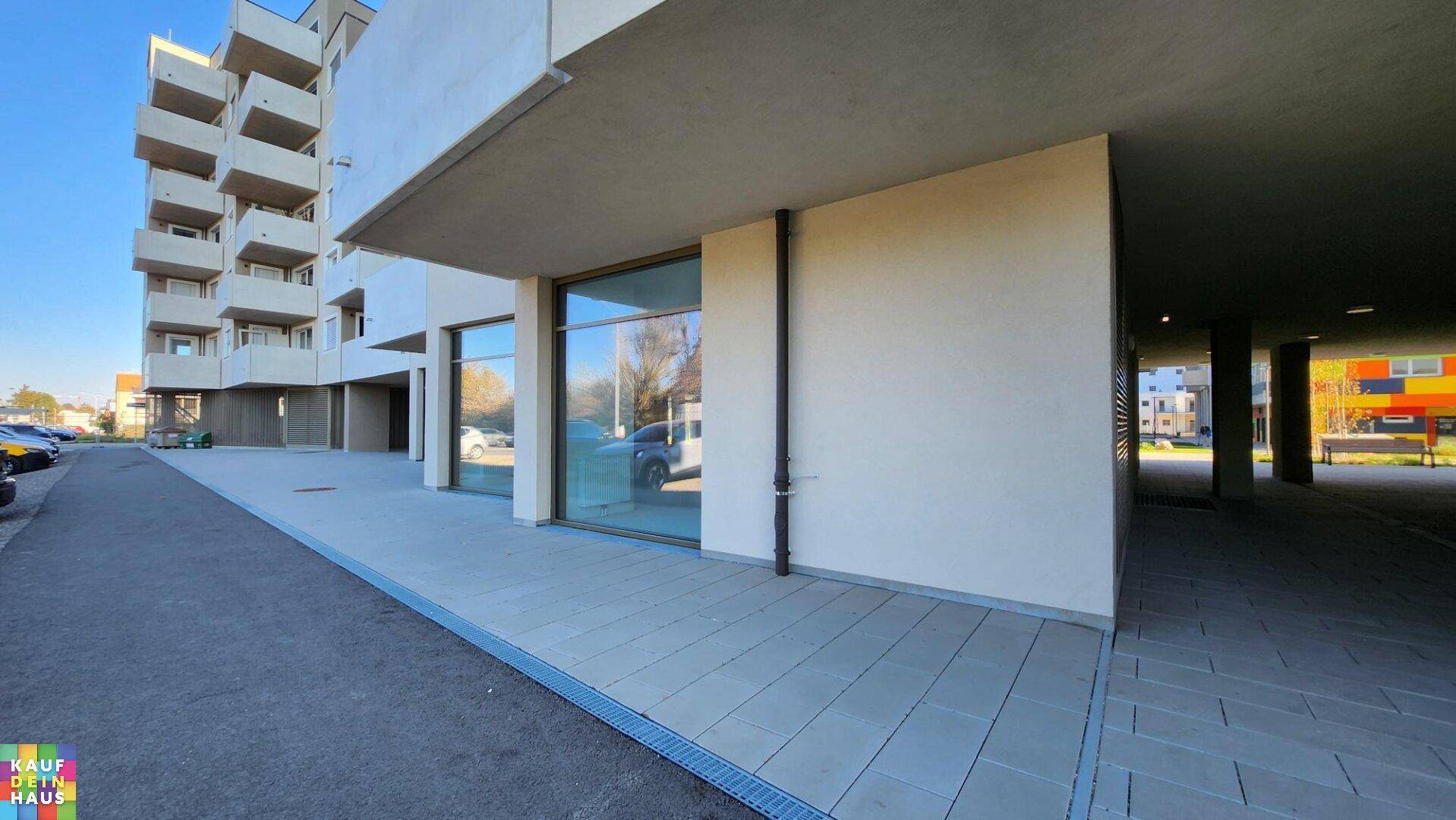 Erdgeschoss eines modernen Gebäudes mit großen Fensterfronten für Gewerbeflächen und überdachtem Eingangsbereich.